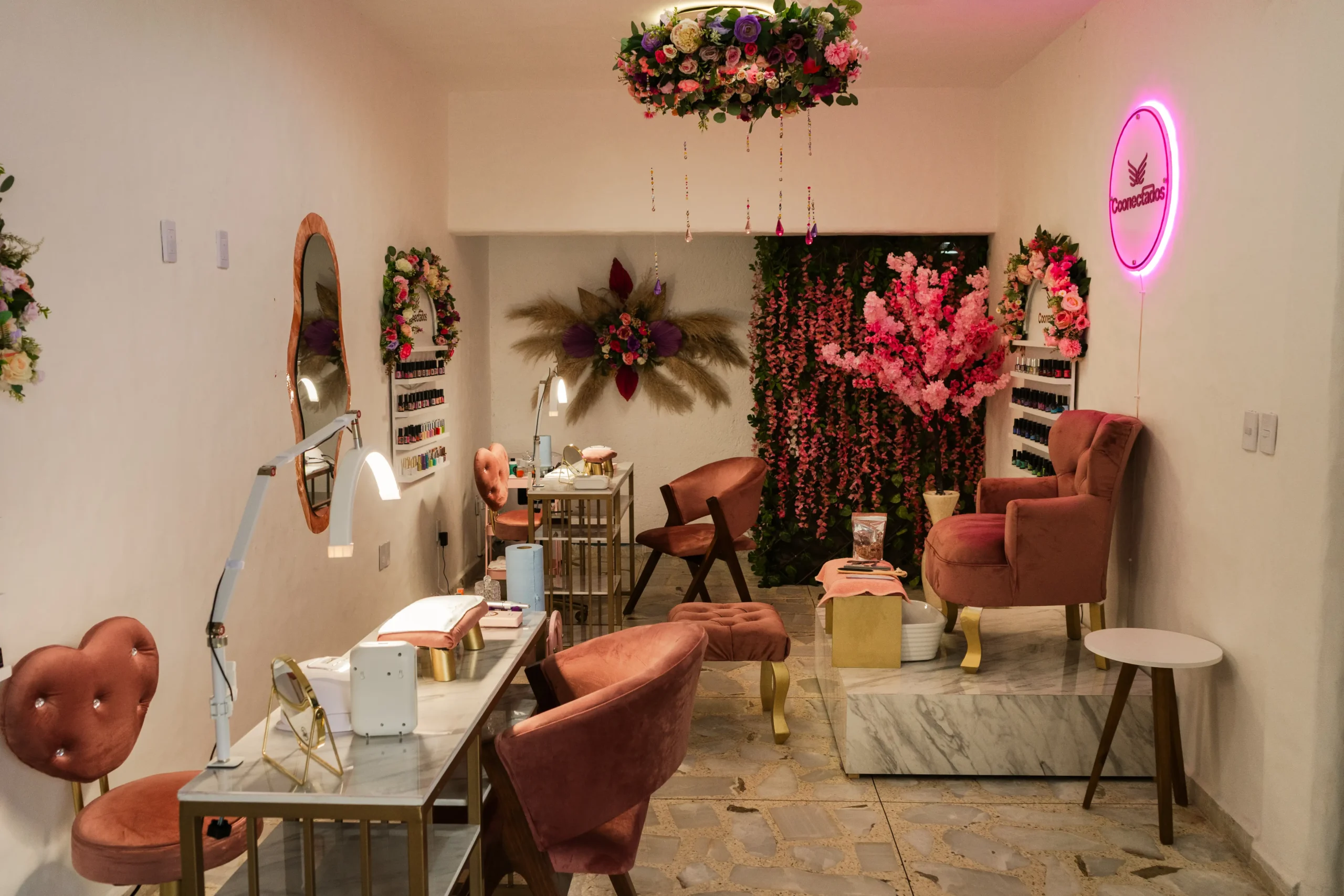 Área interior de belleza y uñas de Conectados Spa en Cuernavaca con decoración floral y mobiliario en tonos rosados